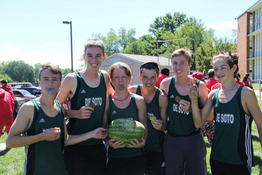 The boys varsity team poses with their medals and watermelon trophy on Saturday, Sept. 10 at Bishop Miege