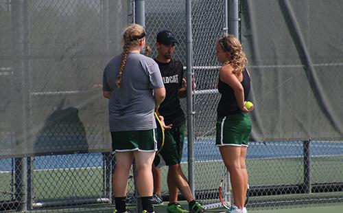 Senior Emily Euler (right) and junior Kelsey Heer get advice from head coach Justin Hoffman durning a changeover of a match at the Wildcat Invitational on Sept. 24