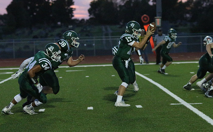 Junior quarterback Bryce Mohl receives a snap as running backs senior Mason Clark and junior Darren Winans anticipate the handoff.