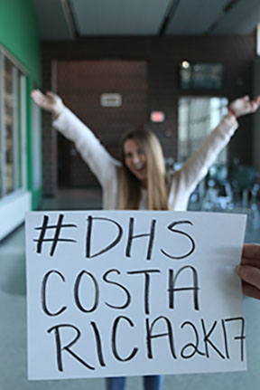 Sophomore Caroline Whipple poses for a picture behind poster labeled #DHSCostaRica2k17