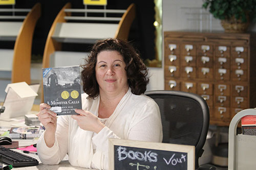 Head librarian and Books to Movies club director Jennifer Sosna holds up a copy of "A Monster Calls," the club's most recent read.