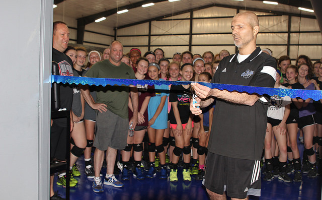 Mike Crist cuts the ceremonial ribbon at the end of the dedication of the Mike Crist Gymnasium on May 10 with Dynasty Volleyball coaches and players of all ages celebrating the occasion.
