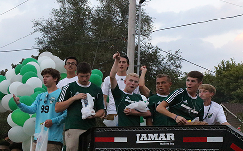 The De Soto High School varsity boys' soccer team cheer from the top of the soccer float on Sept. 20.