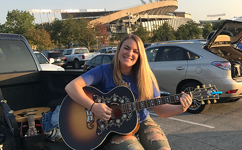 Senior Carly Newhouse plays her guitar outside of Kauffman Stadium.