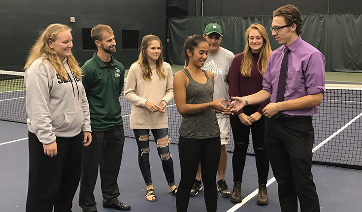 Sophomore Issa Sullivan receives the Channel 41/Hyvee Athlete of the Week from a Hyvee representative while before practicing at Kansas City Racquet Club on Oct. 10. 