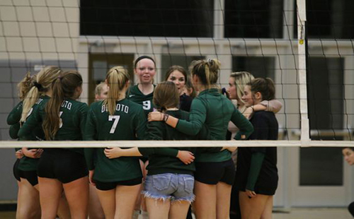 The De Soto High School varsity volleyball team huddles at a home game against Ottawa High School.