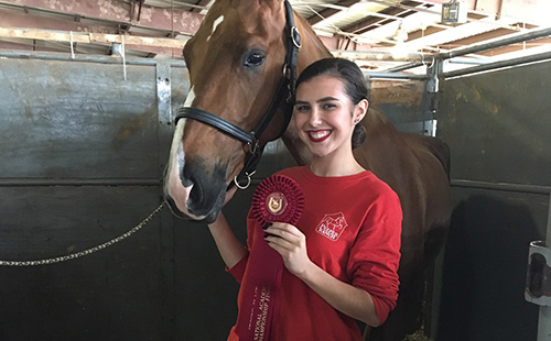 Junior Taylor Hoffman poses with her horse, Remi, and her second place ribbon for horsemanship.