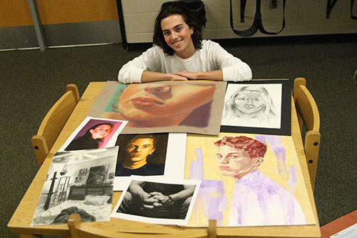 Senior Sam McGuire poses with his college admissions portfolio. Photo by Rylee Wilson.