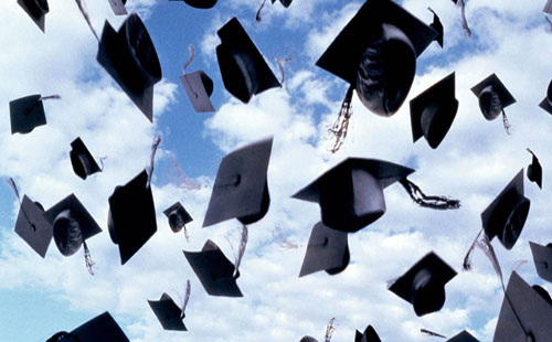 A group of graduates throw their caps into the air.