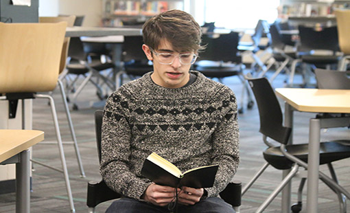 Junior Matthew Jones reads a poem he wrote to the Poetry Slam group in the media center during seminar on April 19.