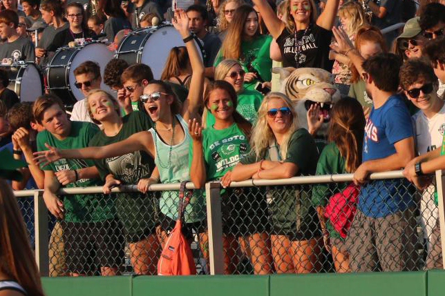 Senior Dravhen Moore stands in the student section with her arms in the air as she cheers on the football team at the Fall Festival on Aug. 2