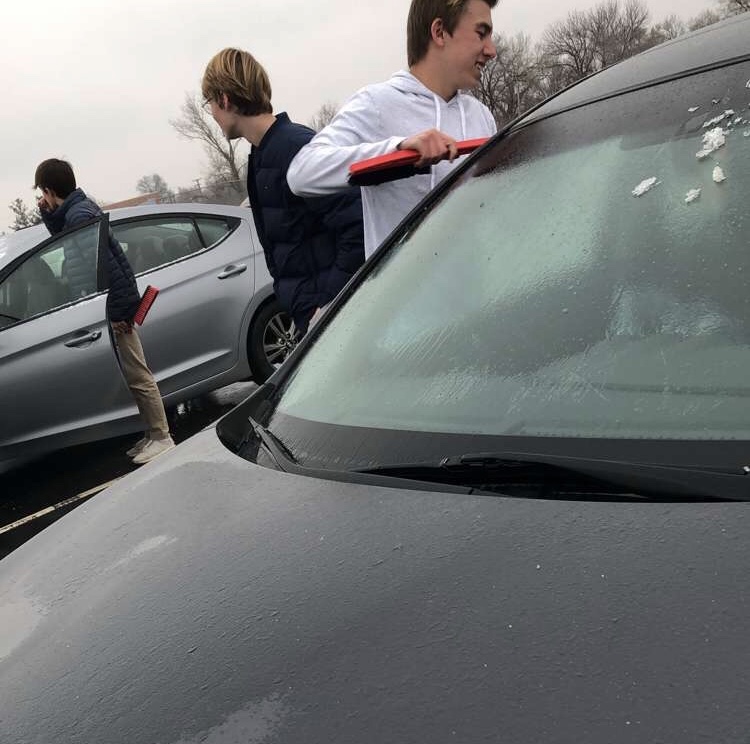 Students Sean Ferrel, Brent Smith and Kyle Smith help scrape ice from car windshields after school was dismissed Wednesday Feb. 6.