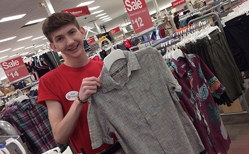 Senior Jacob Ward, who works as a style consultant at the Target on Shawnee Mission Parkway holds up a shirt from the men’s section on June 17. 