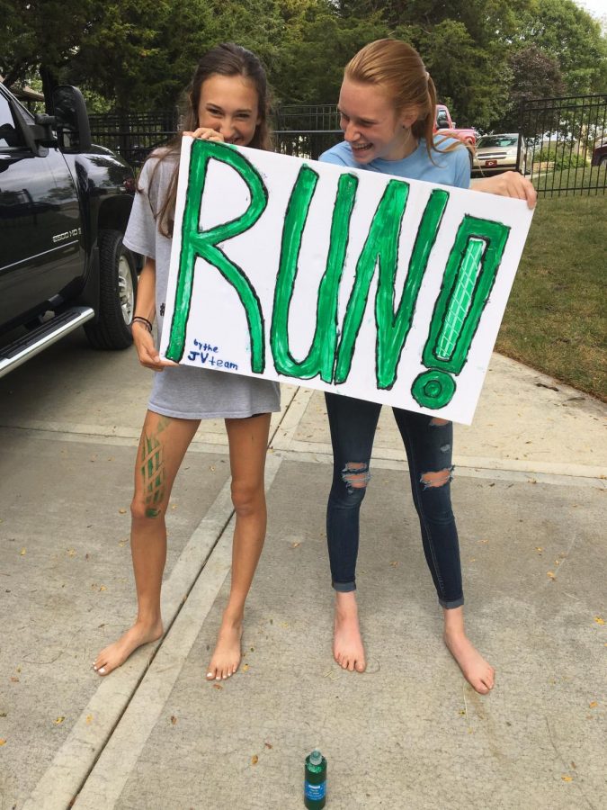 Junior cross country runners Lane Hileman and Erin Pickert pose with a sign they made at a team dinner on Sept. 17, 2017 for a homecoming parade. 