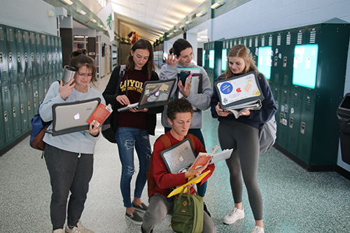 De Soto High School seniors display the realities of senior year while holding all of their homework, coffee, books and MacBooks on Nov. 7, 2019. 