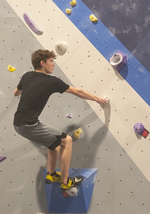 Sophomore Ryan Handley prepares to make a jump to the next hold while rock climbing at Sequence climbing gym. 