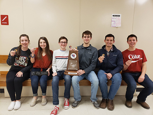 Scholars Bowl UKC team poses with medals and trophy