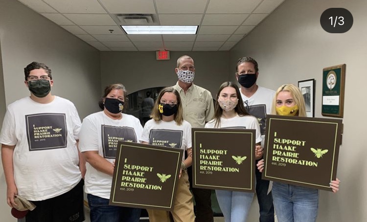 Senior Isabel Haake (center) poses with supporters after successfully convincing the De Soto City Council to allow her family’s prairie restoration project. 