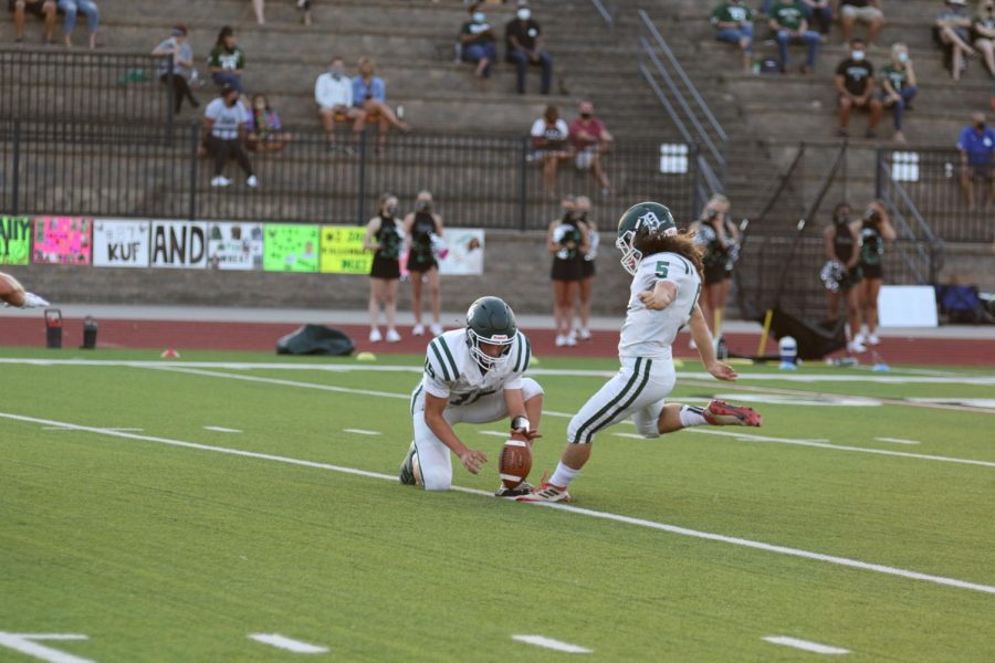 Senior Tyler Schultze holds the ball for senior Luke VanBooven as he kicks a field goal during a game against Lawrence Free State High School on Sept. 4, 2020.